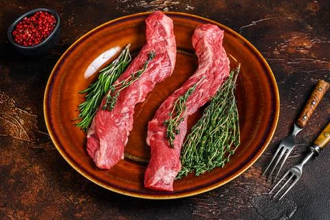 Raw flank beef meat steak on a plate. Dark background. Top view Stock Photos