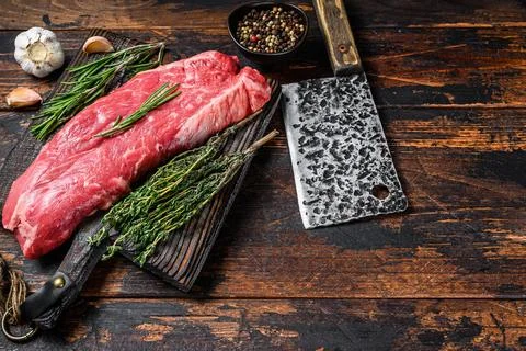 Raw flank beef meat steak on a cutting board with cleaver. Dark wooden Stock-Fotos