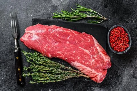 Raw flank beef meat steak. Black background. Top view Stock Photos