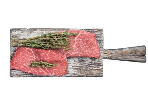 Raw flatiron steaks with thyme on rustic wooden board and carving fork top .. Stock Photos