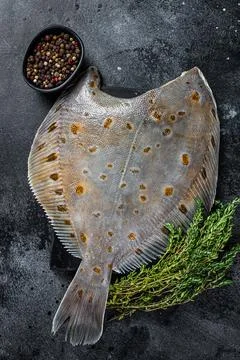 Raw flounder flatfish fish on marble board with thyme. Black background. Top Stock Photos