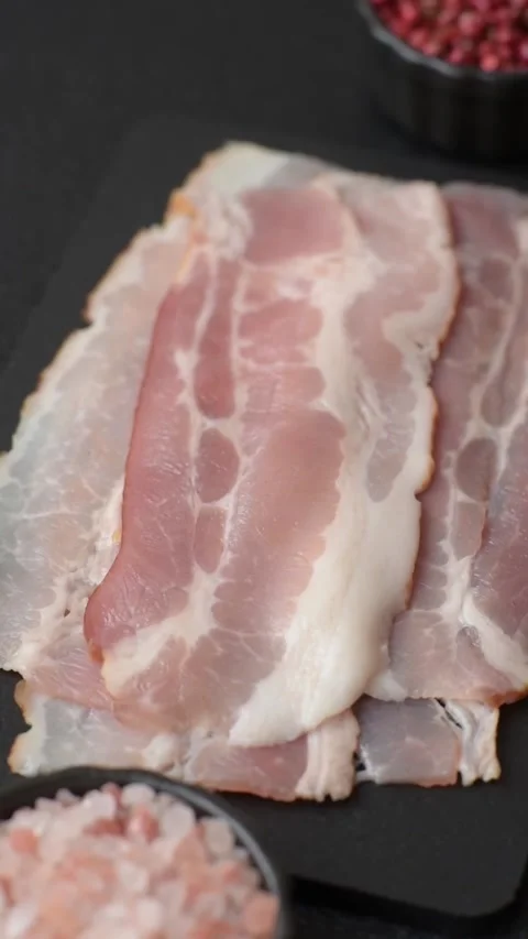 Raw fresh bacon slices with layers of meat or prosciutto with salt and spices. R Stock-Footage 335377636