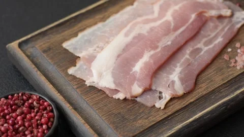 Raw fresh bacon slices with layers of meat or prosciutto with salt and spices. R Stock-Footage 335377648