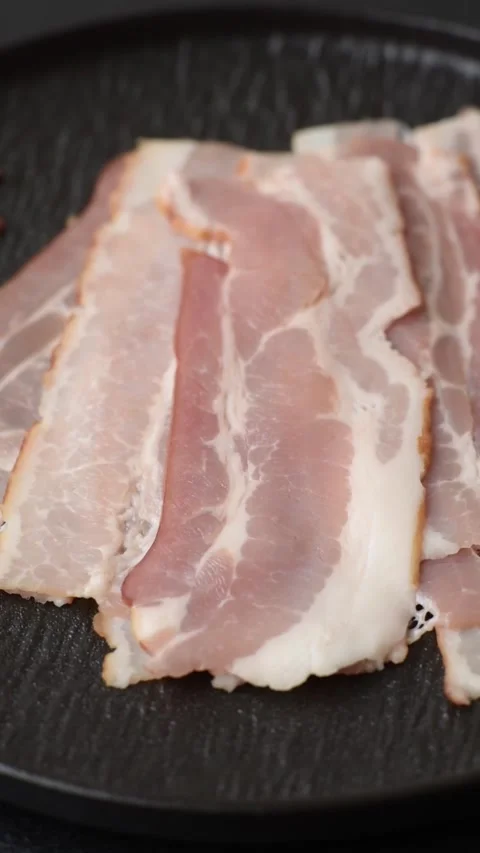 Raw fresh bacon slices with layers of meat or prosciutto with salt and spices. R Stock-Footage 335377652