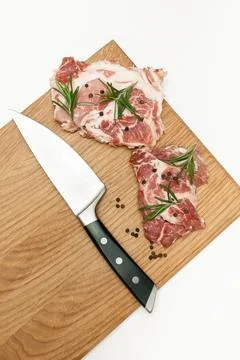 Raw fresh beef meat steaks with rosemary, pepper and knife on cutting board.. Stock-Fotos