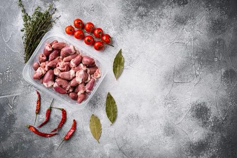 Raw fresh meat chicken hearts in plastic container, on gray stone table backg Stock Photos