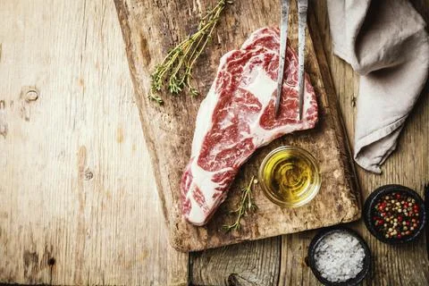 Raw fresh Ribeye Steak, Beef meat with seasoning and fork on wooden background, Stock Photos