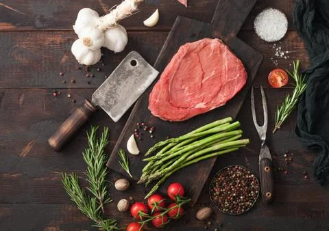 Raw fresh slice of beef braising steak on chopping board with garlic Foto stock