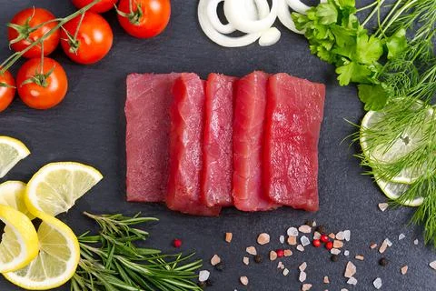 Raw fresh tuna slice in the kitchen and decorates with herbs Foto stock
