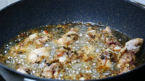Raw fried leg chicken  boiled food palm oil in black teflon induction pan Stock Footage 89513357