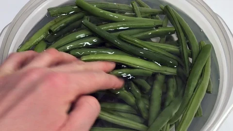 Raw green string beans on water in a plastic bowl on white background. Stock-Footage 86131953