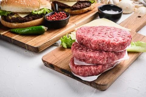 Raw ground beef meat cutlets for burger on white textured background Stock Photos