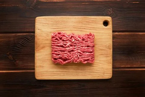 Raw ground beef, minced beef, or beef mince on cutting board on wooden backgr Stock Photos