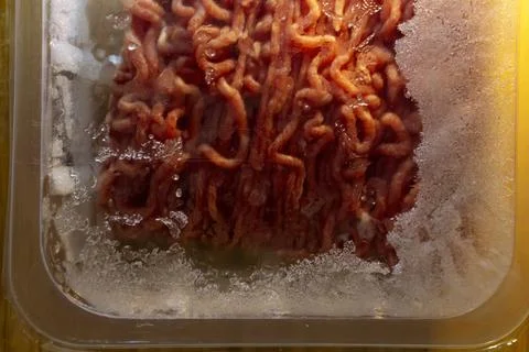 Raw ground beef in plastic container with frost close up 스톡 사진