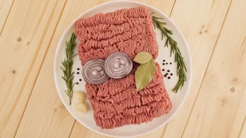 Raw ground beef with spices rotating on a wooden table Stock Footage 337011689