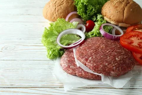 Raw ground beef with vegetables and bread on white wood Stock Photos