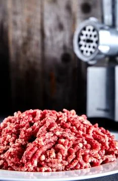 Raw ground beef on a white plate with meat grinder Stock Photos