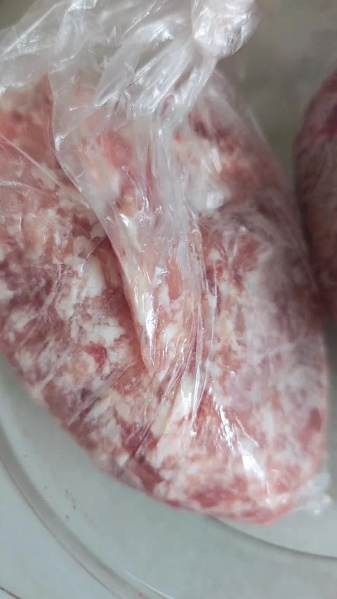Raw ground meat in plastic packaging displayed on a clean kitchen countertop Stock Footage 340557477