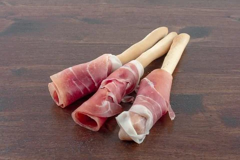 Raw ham wrapped on breadstick Stock Photos