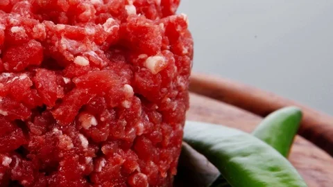 Raw hamburger cutlet with sprouts and chilli pepper on wooden plate 스톡 동영상 70444627