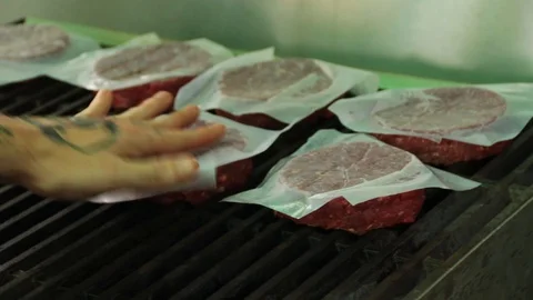 Raw hamburger patties being placed on a hot grill Stock Footage 127715916