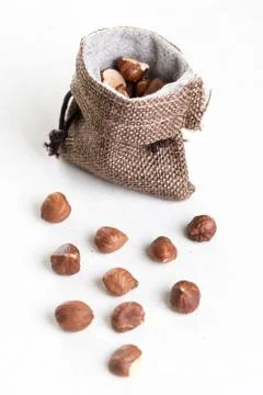Raw hazelnuts on white background and jute drawstring pouches bag Foto stock