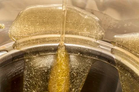 Raw honey go down from a container for the processing Stock Photos