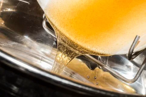 Raw honey go down from a container for the processing Stock Photos