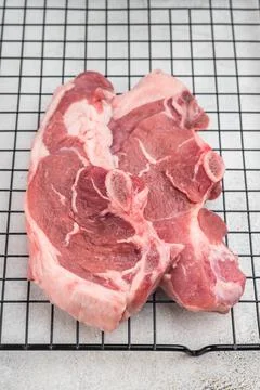 Raw lamb chump chops with bone placed on cooling rack with fresh rosemary, .. Stock Photos