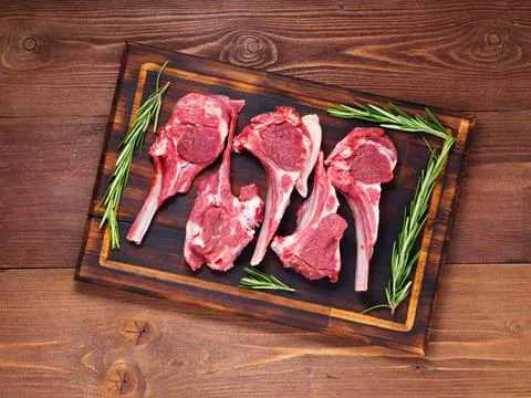 Raw lamb cutlets on bone on dark brown wooden background, lamb ribs, top view. Foto stock
