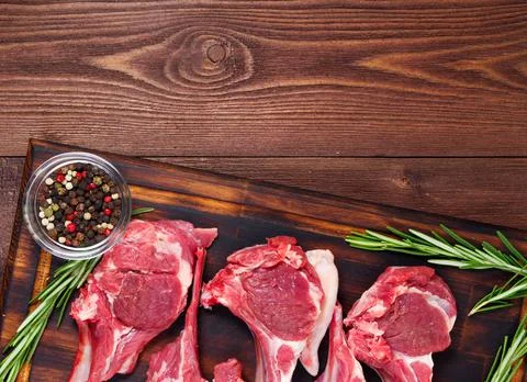 Raw lamb cutlets on bone on dark brown wooden background, lamb ribs, top view Stock Photos