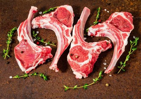 Raw lamb cutlets on bone on dark metallic background, side view, close up Stock Photos