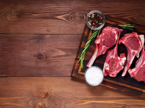 Raw lamb cutlets on bone on dark brown wooden background, lamb ribs, top vi.. Stock Photos