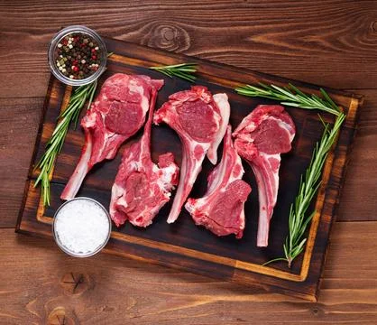 Raw lamb cutlets on bone on dark brown wooden background, lamb ribs, top view Stock Photos