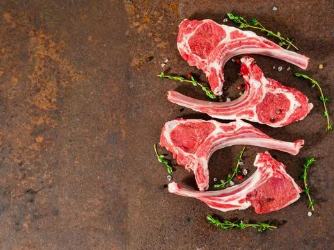 Raw lamb cutlets on bone on dark metallic background, top view, empty space. Stock Photos