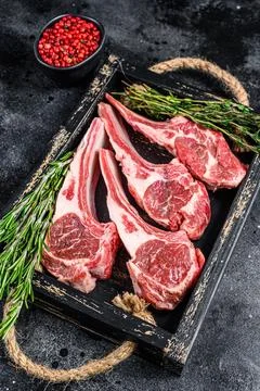 Raw lamb meat chops steaks in a wooden tray. Black background. Top view Stock Photos