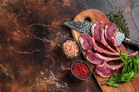 Raw lamb, mutton chops steaks on a wooden board. Dark background. Top view. Copy Stock Photos
