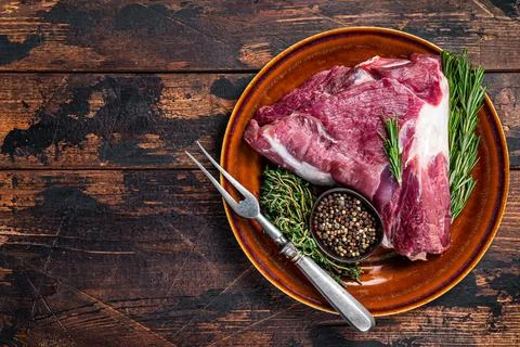 Raw lamb mutton thigh or leg with rosemary and thyme in rustic plate. Dark Stock Photos