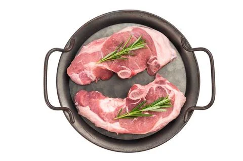 Raw lamb rump steaks with bone served in rustic metal pan with fresh rosema.. Stock Photos