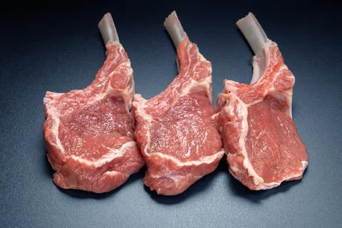 Raw lamb saddle meat on bone top view on black background Fotos Stock