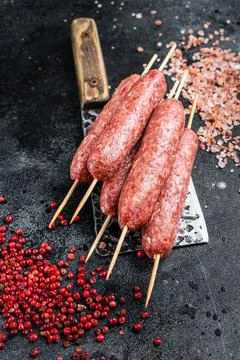 Raw lula or kofta kebabs skewers on a butcher cleaver with salt and pepper Stock Photos