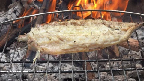 Raw Mackerel fish fillet is flipped on the grill grid over the open fire Stock Footage 208679864