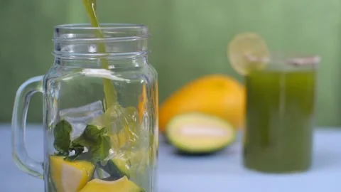 Raw mango lemonade with ice cubes and mint leaves pouring in a glass jar - Su... Stock Footage 154395909