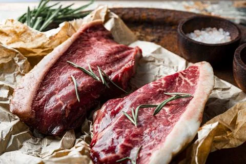 Raw marbled beef steaks and seasonings for their preparation on the old woo.. Stock Photos