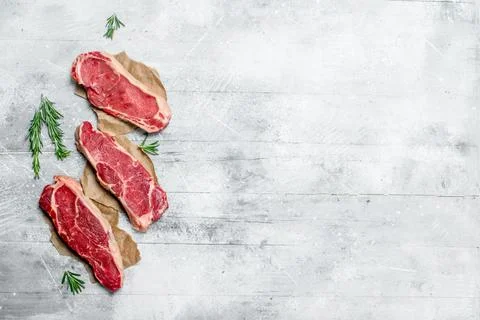 Raw marbled beef steaks with fragrant rosemary. Stock Photos