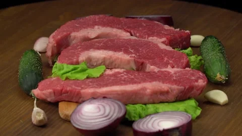 Raw marbled beef steaks with lettuce, red onion, garlic and cucumber Video stock 147075218