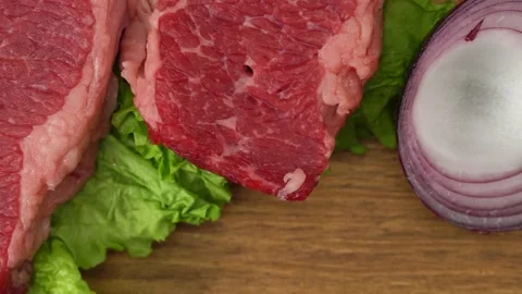 Raw marbled beef steaks with lettuce, red onion, garlic and cucumber Stock Footage 147121114
