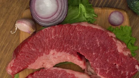 Raw marbled beef steaks with lettuce, red onion, garlic and cucumber Видео 147121120