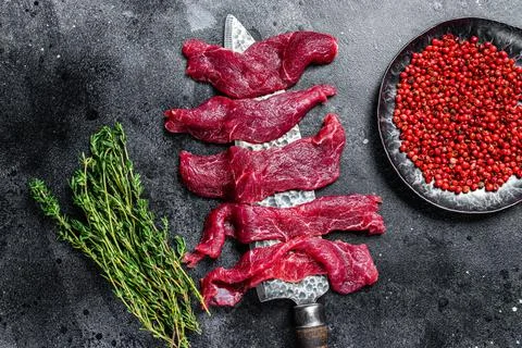 Raw marbled meat cut into thin strips for beefstroganoff. Black background. Top Stock Photos