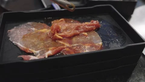 Raw marinated beef slices on a black plastic tray being handled with metal .. Stock Footage 334583655